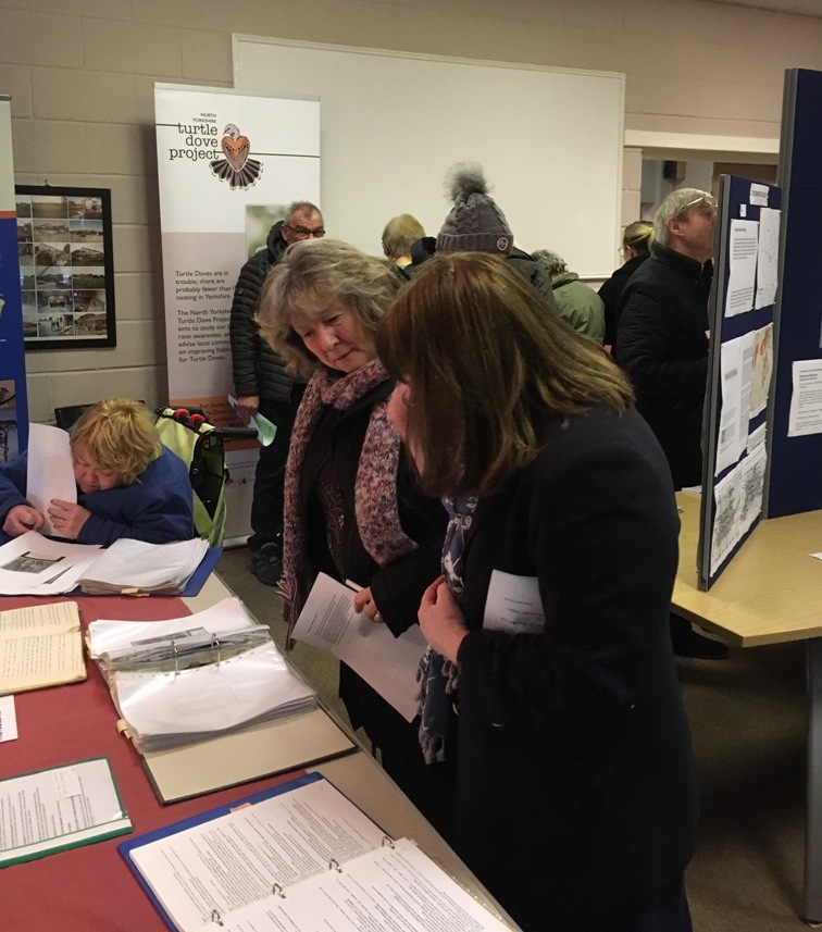 People looking at photos and other information about the village